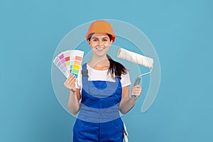 Young woman in coverall posing with color palette and roller paint brush