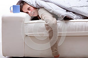 Young woman covered in a duvet passed out on a sofa photo