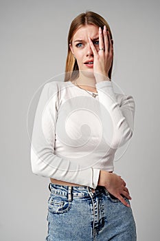 Young Woman Covering Face With Hands against gray background