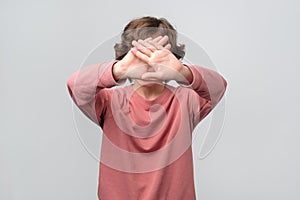 Young woman covering face with hands trying to stay anonym.