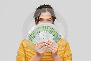 Young woman covering her face with euro money