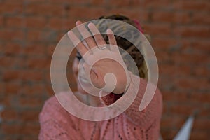 Young woman covering her face with palm saying no. Girl denying proposal, making stop gesture with her hand. Studio shot