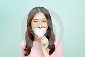 Young woman covering her mouth with a heart