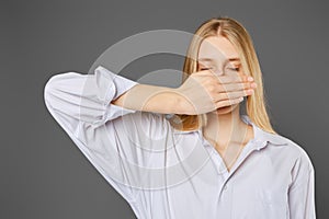 Young woman covers her mouth with her palm