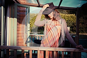 Young woman with cowboy hat stading on the porch of cabin