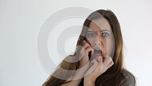 Young woman cowering with fear on white background