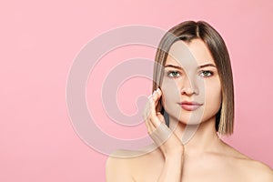 Young woman with cream around eye on pink background, space for text