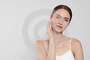 Young woman with cream around eye on white background, space for text