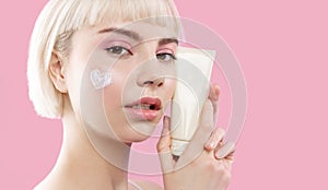 Young woman with cream on ideal smooth cheek skin hold mockup jar
