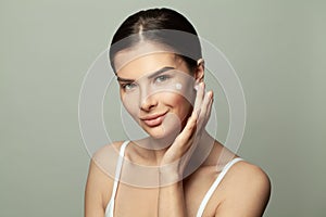 Young woman with creame on her face on white background