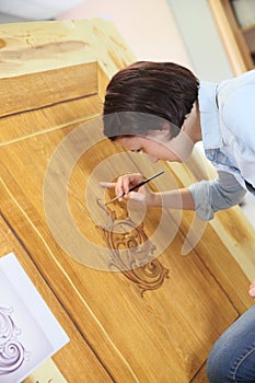 Young woman creating artwork in wood