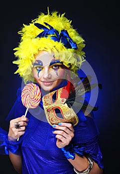 Young woman with creative visage with lollipop and mask. Party and carnival.