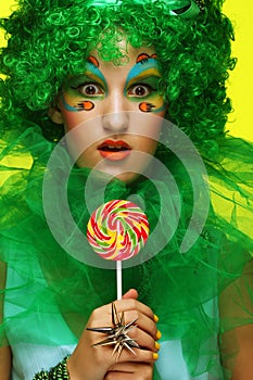 Young woman with creative visage with lollipop. Party and carnival. Bright wig.