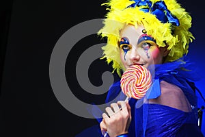 Young woman with creative visage with lollipop. Party and carnival. Bright wig.