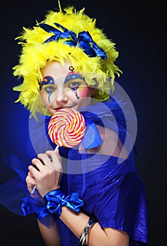 Young woman with creative visage with lollipop. Party and carnival. Bright wig.