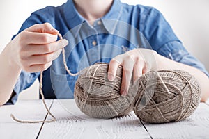 Young woman crochets a warm blanket with beige wool