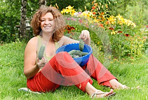 Young woman with crop of cucumbers