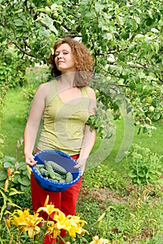 Young woman with crop of cucumbers