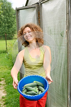 Young woman with crop of cucumbers