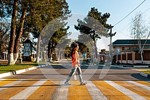 A young woman crosses a pedestrian crossing. Empty road and streets. Side view. Concept of traffic rules