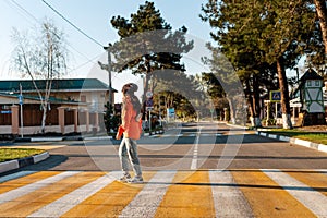 A young woman crosses a pedestrian crossing. Empty road and streets. Sunny. Concept of traffic rules