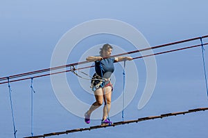 Young woman crossing a chasm on a rope bridge