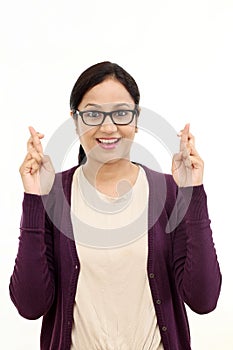 Young woman crossing fingers against white