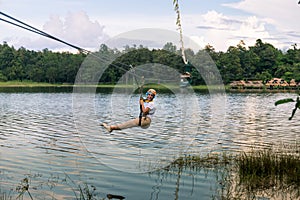 Young woman crossing a lake in zip line in Chiang Mai