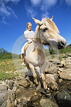 Young woman crossing a river by horse