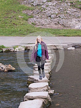 Young woman crossing stepping stones sovedale