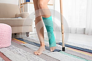 Young woman with crutch and broken leg in cast