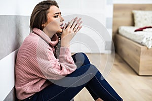 Young woman after cry sitting on whte floor at home in depression. A woman sitting alone and depressed. The depression woman sit o