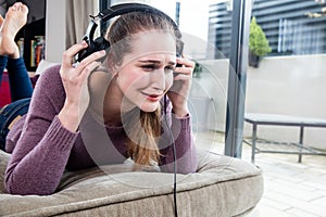 Young woman crying in removing her headphones for noisy music