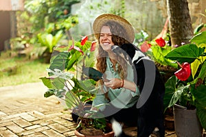 Young woman cuddling and snuggling with her pet dog laughing. Caucasian female gardener with trowel planting flowers in