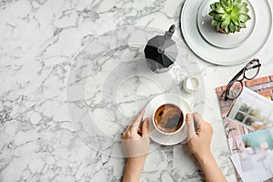 Young woman with cup of delicious hot coffee at table