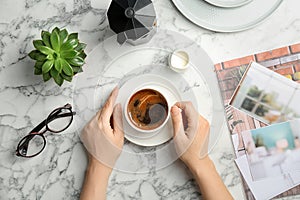 Young woman with cup of delicious hot coffee at table