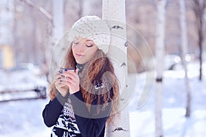 Young woman with a cup of hot drink in winter park