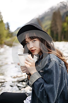 Young woman with cup outdoor portrait in soft sunny daylight