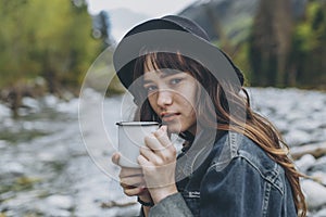Young woman with cup outdoor portrait in soft sunny daylight