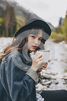 Young woman with cup outdoor portrait in soft sunny daylight