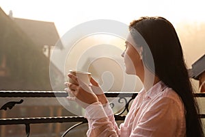 Young woman with cup of tea enjoying beautiful view