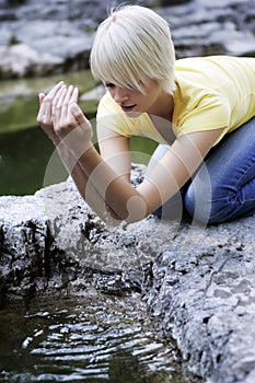 Young woman cupping water from a rock pool