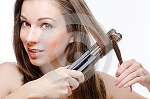 Young woman curling hair with hair straightener