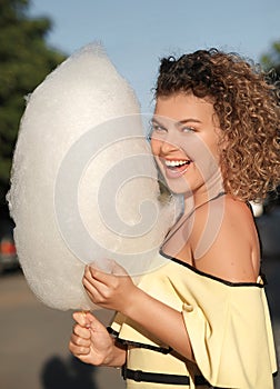 Mujer sonriente ondulado cabello tiene divertido algodón dulce sobre el atardecer 