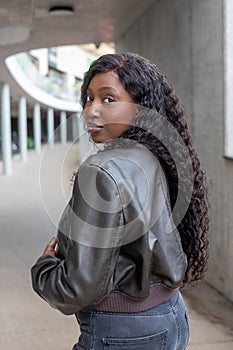 Young Woman with Curly Hair in Leather Jacket Glancing Over Shoulder