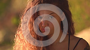 Young woman with curly hair raising eyebrow and making cute mad face.