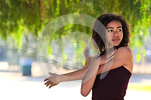 Young woman with curly hair stretching outside