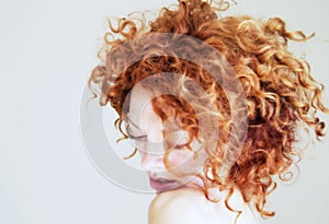Young woman with curly red hair being shy