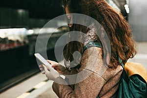 Young woman curly red head girl traveller with backpack using mobile in subway