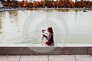 young woman and cute dog by the lake in an urban park. Love for animals concept. Retiro park Madrid